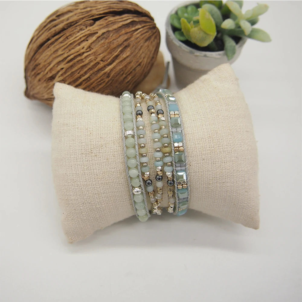 Wrap beaded bracelet on a fabric stand with a ball of nut and plant in the background.