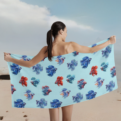 Betta fish towel in light blue held up by model behind her while she is on the beach