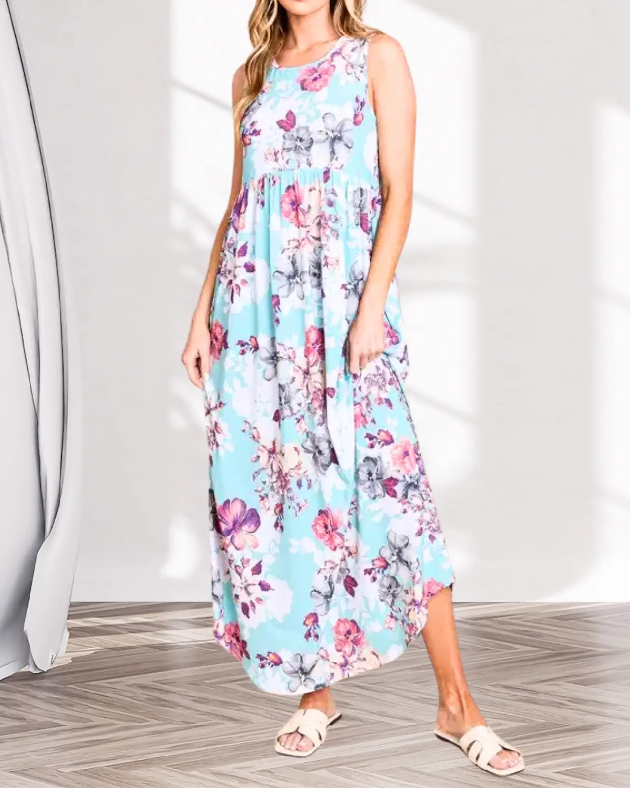 Model is wearing a light blue floral printed sleeveless dress, maxi length with high waistline
