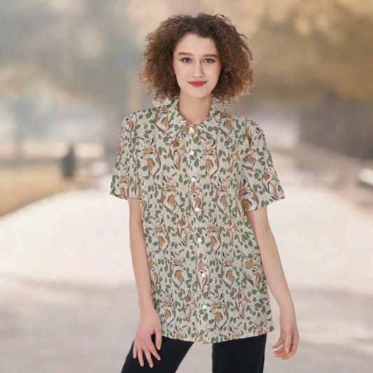 Model is wearing short sleeve button down shirt with print of foxes and foliage on taupe background. Scene is blurry park setting.